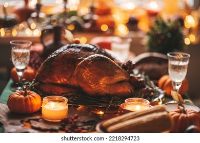 Classic USA Thanksgiving Day Dinner With Holiday Autumn Decor And Candles. Family Dining Room Table Set With Delicious Golden Roasted Turkey On Platter Garnished Rosemary And Fresh Small Pumpkins