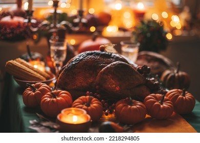 Classic USA Thanksgiving Day Dinner With Holiday Autumn Decor And Candles. Family Dining Room Table Set With Delicious Golden Roasted Turkey On Platter Garnished Rosemary And Fresh Small Pumpkins