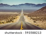 Classic vertical panorama view of an endless straight road running through the barren scenery of the American Southwest with extreme heat haze on a beautiful hot sunny day with blue sky in summer