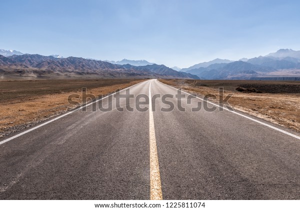 Classic vertical panorama view of an endless straight\
road running through the barren scenery of the American Southwest\
with extreme heat haze on a beautiful hot sunny day with blue sky\
in summer 
