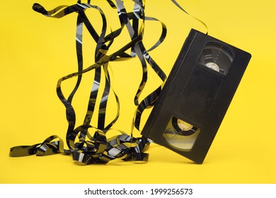 Classic VHS Videotape On A Yellow Background. The Magnetic Tape Outside The Case.