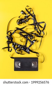 Classic VHS Videotape On A Yellow Background. The Magnetic Tape Outside The Case.