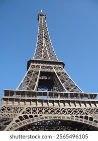 Classic view of the Eiffel Tower in Paris, showcasing its iconic iron lattice structure and architectural beauty under a vibrant blue sky