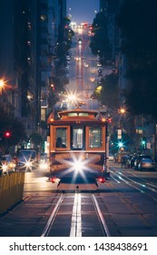 Classic view of historic traditional Cable Cars riding on famous California Street at night with city lights, San Francisco, California, USA