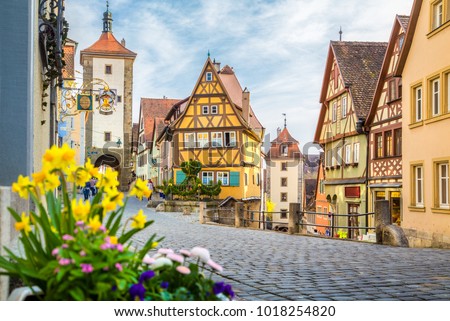Classic view of the medieval town of Rothenburg ob der Tauber with blooming flowers on a beautiful sunny day with blue sky and clouds in springtime, Bavaria, Germany
