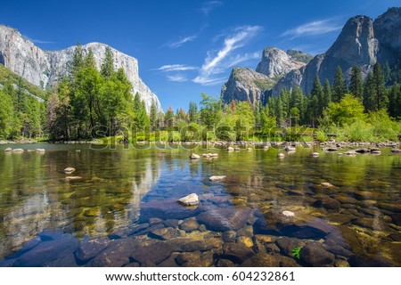 Classic view of scenic Yosemite Valley with famous El Capitan rock climbing summit and idyllic Merced river on a sunny day with blue sky and clouds in summer, Yosemite National Park, California, USA