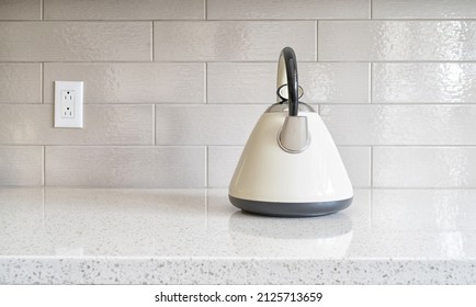 Classic vintage kettle on a granite counter top against a ceramic background