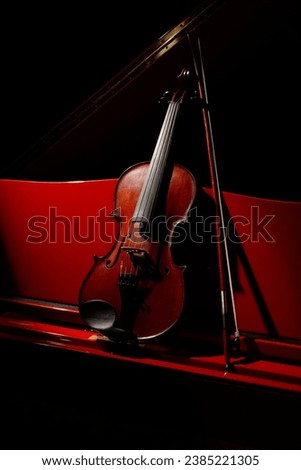 Classic Violin and bow on a red piano in a dark. Viola or fiddle on piano notes. Music concept. Selective focus