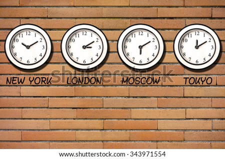Classic wall clocks for different timezones on wall of bricks              
