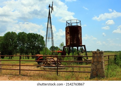 A classic Western ranch scene with windmill, stock tank and old tractor in the Texas Hill country