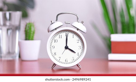 Classic white clock on a table. The clock hand points to 4 or 16, close up photo