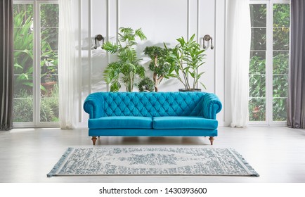 Classic White Wall Background, Blue Armchair Windows And Garden View, Furniture Detail With Vase Of Green Plant. Carpet On The Parquet Style. Home Interior Living Room.