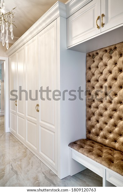 Classic white
wardrobe with seating in contemporary bright hallway. Classic
furniture. Carriage coupler closet
bench
