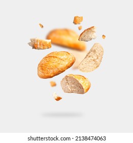 Classic white wheat bread flying on gray background. Round whole and pieces crispy fresh bread, healthy organic food, traditional pastries, bakery. Creative food concept for advertising, design 