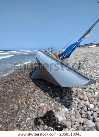 Classic wooden sailboat or yacht stranded on a beach after a storm.
