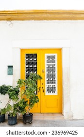The classical architecture of the Mediterranean (Greece, Italy, Spain, Cyprus, Portugal).  Wooden yellow door on the white buildings and plants. Postal box. 