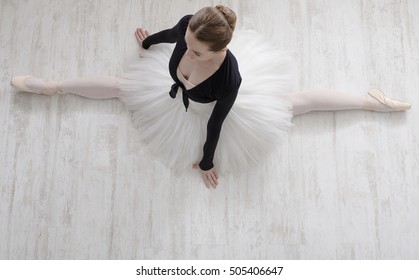 Classical Ballet Dancer Portrait. Beautiful Graceful Ballerine In Tutu Skirt Practice Split Ballet Position In Class Room Background. Ballet Class Training, High-key Soft Toning. Top View From Above