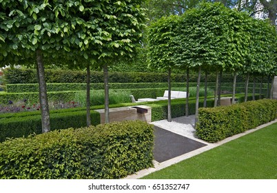 A Classical Garden With An Avenue Of Yew, Box And Hornbeam Leading To A Water Feature And Sculpture