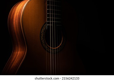 Classical guitar close up, dramatically lit on a black background with copy space - Shutterstock ID 2156242133