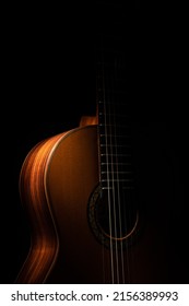 Classical guitar close up, dramatically lit on a black background with copy space.  
