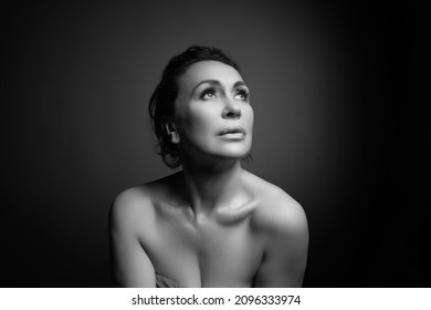 Klassisches Headshot-Portrait einer sinnlichen 50-jährigen Frau auf grauem Studiohintergrund. Monochrome Aufnahme.