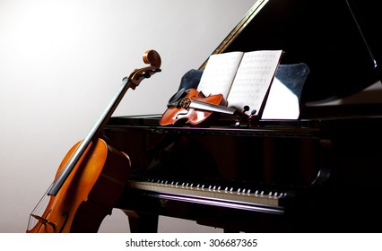 Classical music concept: cello and violin leaning on a piano