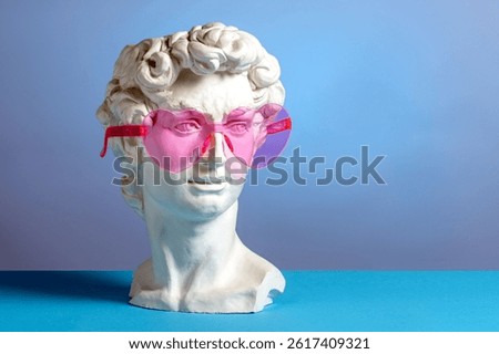 A classical plaster bust of David wearing playful pink heart-shaped sunglasses, blending antique sculpture with modern pop art aesthetics