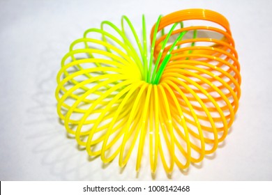 Classical slinky spring toy isolated on the white background. Slinky Toy Curved Rainbow Pattern