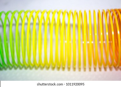 Classical slinky spring toy isolated on the white background. Slinky Toy Curved Rainbow Pattern