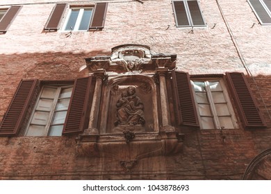 Classical statue on building facade in Siena