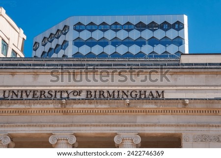 A classical University of Birmingham facade with UNIVERSITY OF BIRMINGHAM inscribed, contrasts a modern building with a honeycomblike design and blue windows in Birmingham, UK.