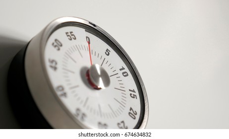 Classical vintage kitchen countdown timer close up shot with analog clock face and red remaining time display, 0 minutes left, low depth-of-field with blur