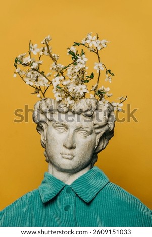 Classical white bust of a young man wearing a turquoise shirt, with a blooming tree branch sprouting from his head.