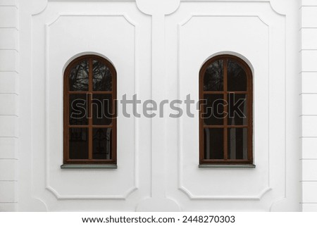 Classical windows with arches and decorative elements in white stone wall. Background photo texture