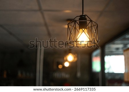 Classing ceiling lighting lamp with metal cage that glowing in warmlight shade. Interior decoration object equipment, Close-up and selective focus.
