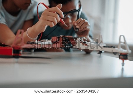 Classmates assembling robotic kit, working with circuit board at home.