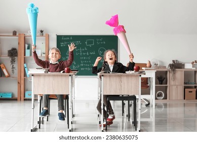 Classmates with school cones sitting at desks in classroom - Powered by Shutterstock