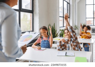 Classmates sit at desks and isten to teacher during school lessoin  bright classroom  - Powered by Shutterstock