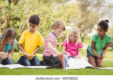 Classmates sitting in grass and reading books on campus - Shutterstock ID 309238202