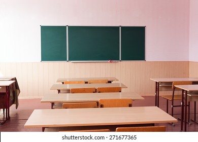 Classroom with empty wooden desks and with green board , in scool
