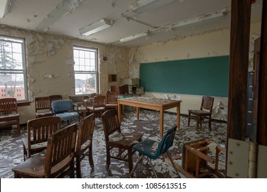 Classroom with peeling, chipping paint on wood desk and chairs in abandoned school.