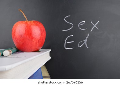 Classroom With Red Apple,books And Handwriting In White Chalk On Blackboard Saying Sex Education