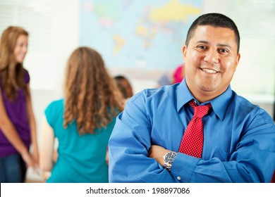 Classroom: Smiling Hispanic Teacher With Arms Crossed