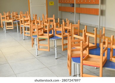 Classroom for young students with tiny chairs on desks, empty school room with bright tiled floor, playful and organized space for elementary learning activities