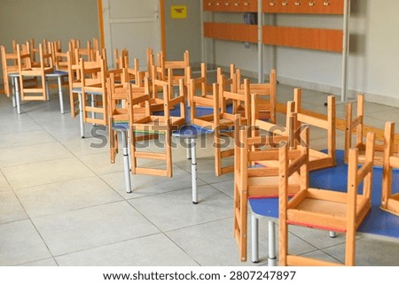 Classroom for young students with tiny chairs on desks, empty school room with bright tiled floor, playful and organized space for elementary learning activities