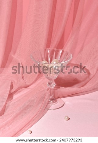Classy cocktail glass, pastel pink tulle drapery in the background, Art Deco style elegant party.
