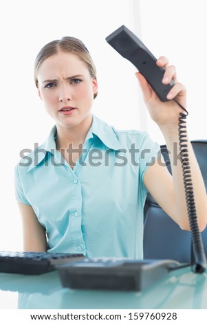 Classy furious businesswoman hanging up phone in bright office
