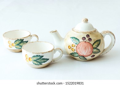 A Classy Tea Set - Two Cups And A Tea Pot With Floral Drawings Isolated On White