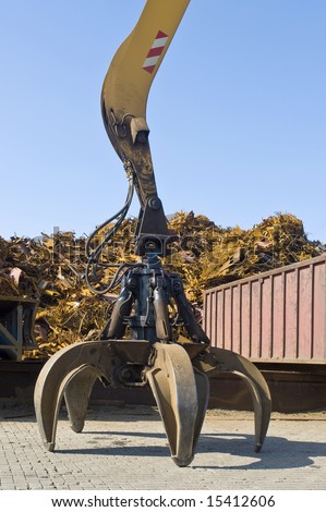 A claw, attached to a huge crane in front of a scrap heap