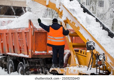 Claw Loader Vehicle Removes Snow From The Road.  Uniformed Community Service Worker Helps Load Snow Into A Truck.